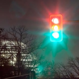 Eine Ampel leuchtet in einer Aufnahme mit Langzeitbelichtung am Morgen vor dem Reichstagsgebäude in allen drei Phasen.