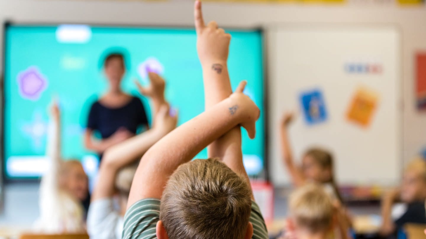 Kinder sitzen am ersten Schultag nach den Sommerferien in einem Klassenraum.