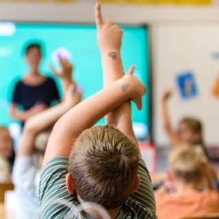 Kinder sitzen am ersten Schultag nach den Sommerferien in einem Klassenraum.