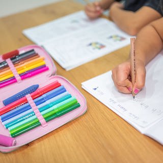 Ein Grundschüler und eine Grundschülerin sitzen in einem Wohnzimmer am Tisch und erledigen Schulaufgaben. In Baden-Württemberg beginnt am 9. September wieder die Schule.