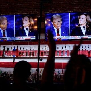 Besucher einer Bar verfolgen das TV-Duell zwischen den Präsidentschaftskandidaten Kamala Harris und Donald Trump im Fernsehen.