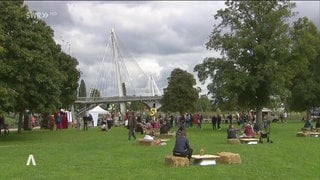 Viele Menschen bei einem Fest auf einer Wiese am Rhein