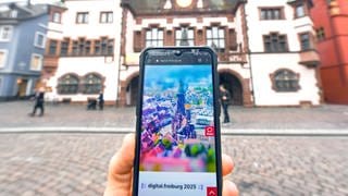 Auf einem Smartphone vor dem Freiburger Rathaus ist die Webseite "Digital.freiburg.de" geöffnet.