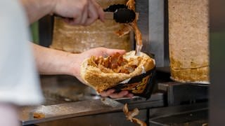 Ein Mitarbeiter einer Dönerbude legt Fleisch in einen Döner. Die Heilbronner CDU hat eine Dönerobergrenze für die Stadt gefordert.