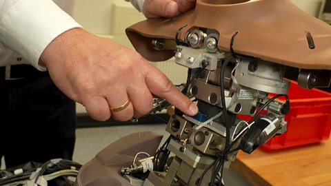 Eine Hand zeigt auf die Technik in einer Puppe: Ein Crashtest-Dummy hat im Inneren sehr viele Sensoren verbaut.