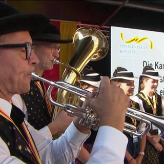 Blasmusiker und Sängerinnen in Tracht stellen auf einer Bühne in Waldkirch gemeinsam einen Weltrekord der ganz besonderen Art auf:  Über sechs Stunden lang spielten und sangen sie das Badnerlied, ohne Pause.