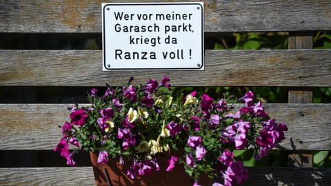 Ein Schild mit der Aufschrift in schwäbischer Mundart "Wer vor meiner Garasch parkt, kriegt da Ranza voll".