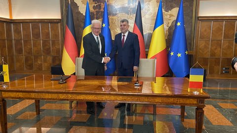 Baden-Württembergs Ministerpräsident Winfried Kretschmann (Grüne) schüttelt dem rumänischen Premierminister Marcel Ciolacu nach dem Unterzeichnen einer gemeinsamen Erklärung in Bukarest die Hand. 