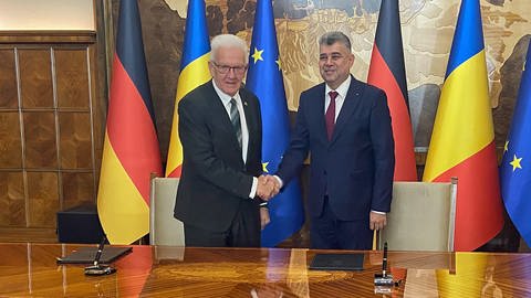 Baden-Württembergs Ministerpräsident Winfried Kretschmann (Grüne) schüttelt dem rumänischen Premierminister Marcel Ciolacu in Bukarest die Hand.