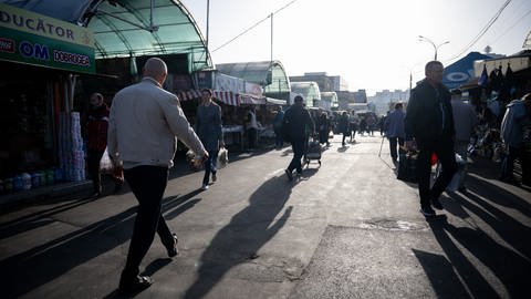 Menschen gehen über einen Markt einer Innenstadt in Moldau. 