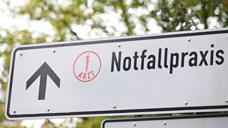 Auf einem Wegweiser an einer Straße in Baden-Württemberg vor einem Krankenhaus steht ein Hinweisschild auf eine Notfallpraxis. Die KVBW plant die Schließung weiterer Notfallpraxen