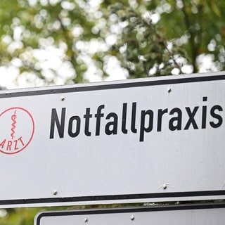 Auf einem Wegweiser an einer Straße in Baden-Württemberg vor einem Krankenhaus steht ein Hinweisschild auf eine Notfallpraxis. Die KVBW plant die Schließung weiterer Notfallpraxen