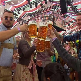 Menschen prosten sich im Bierzelt zu