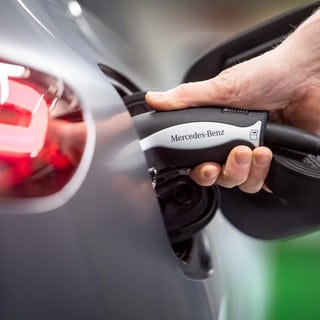 Ein Ladekabel wird an den Mercedes-Benz EQC gehalten. Für die Batterien von E-Autos braucht es etwa seltene Erden. Beim Abbau kann es zu Ausbeutung und Umweltschäden kommen. Amnesty International rügt jetzt alle großen E-Autobauer.