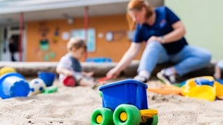 Ein Kind spielt mit einer Erzieherin im Sandkasten einer Kita.