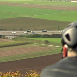 Ein Fahrradfahrer blickt auf eine Autobahn hinab