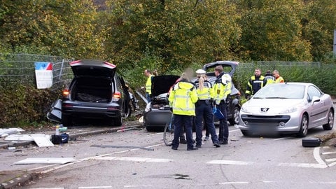 Einsatzkräfte der Polizei stehen in Esslingen an der Unfallstelle neben drei Fahrzeugen. Bei dem schweren Verkehrsunfall sind nach Polizeiangaben drei Personen gestorben.