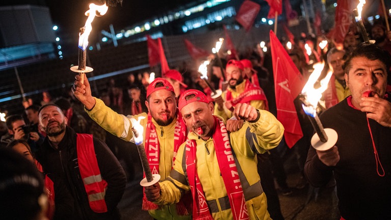 Mitarbeiter von Porsche nehmen vor dem Porsche-Werk in Stuttgart-Zuffenhausen mit Fackeln und Fahnen an einem Warnstreik teil. Die IG Metall ruft ihre Mitglieder in der Metall- und Elektroindustrie zu flächendeckenden Warnstreiks ab Dienstag auf.