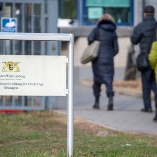 Geflüchtete betreten die Landeserstaufnahmestelle für Flüchtlinge (LEA) in Ellwangen. Das BW-Justizministerium möchte Kommunen mit solchen LEAs entlasten.