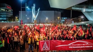 Bereits am Dienstag (29.10.) hat die IG Metall zum Streik aufgerufen. Hier zu sehen: Mitarbeiter von Porsche am Porsche-Werk in Stuttgart-Zuffenhausen mit Fackeln und Fahnen. Die IG Metall ruft ihre Mitglieder in der Metall- und Elektroindustrie zu flächendeckenden Warnstreiks ab Dienstag auf.