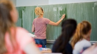 Eine Lehrerin steht vor einer Klasse ander Tafel. Immer mehr Lehrkräfte in Baden-Württemberg kündigen ihren Job.