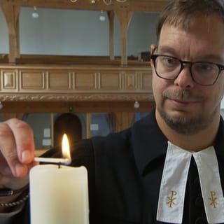 Social-Media-Pfarrer Nicolai Opifanti zündet in der Kirche eine Kerze an.