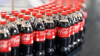 Am Produktionsstandort Mannheim von Coca-Cola Europacific Partners (CCEP) Deutschland werden abgefüllte Coca-Cola-Flaschen über ein Förderband transportiert.