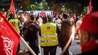 Mitarbeiter von Porsche nehmen vor dem Porsche-Werk in Stuttgart-Zuffenhausen mit Fackeln und Fahnen an einem Warnstreik teil. 