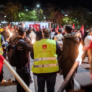 Mitarbeiter von Porsche nehmen vor dem Porsche-Werk in Stuttgart-Zuffenhausen mit Fackeln und Fahnen an einem Warnstreik teil. 