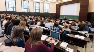 Jura-Studenten sitzen an der Universität Freiburg im Hörsaal in einer Vorlesung.