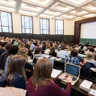 Jura-Studenten sitzen an der Universität Freiburg im Hörsaal in einer Vorlesung.