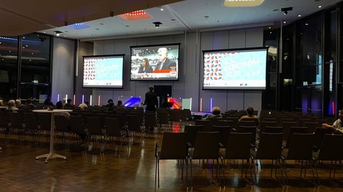 Auf einem großen Bildschirm in einer Halle verfolgen Menschen in Stuttgart die Wahlergebnisse aus den USA.