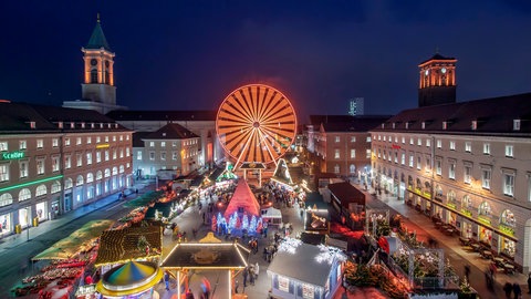 Beim Weihnachtsmarkt auf dem Marktplatz in Karlsruhe dreht sich ein Riesenrad.