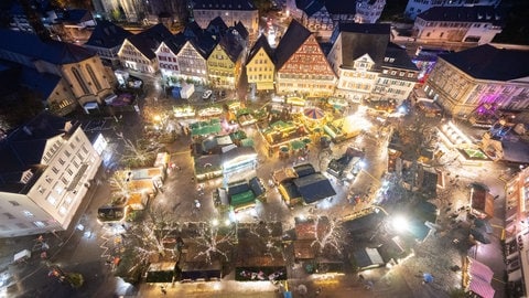 Die Stände des Weihnachtsmarkts Esslingen leuchten am Abend.