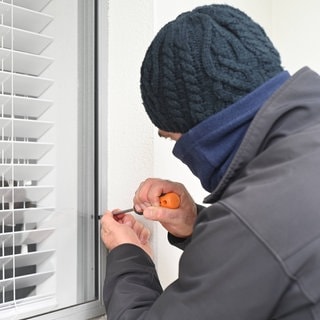 Ein Einbrecher versucht in Fenster aufzubrechen (Symbolbild)