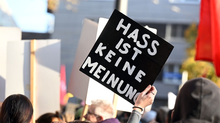 Bei einer Demonstration gegen eine rechte Kundgebung wird ein Plakat in die Höhe gehalten auf dem steht “HASS IST KEINE MEINUNG“