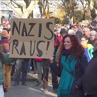 Viele Demonstranten auf einer Demo gegen Rechts mit dem Schild "Nazis Raus!"