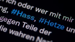 Auf dem Bildschirm eines Smartphones sieht man die Hashtags Hass und Hetze in einem Twitter-Post.