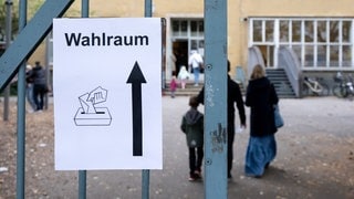 Ein Schild mit der Aufschrift "Wahlraum" hängt an einem Tor vor einem Wahllokal im Stadtteil München-Neuhausen. 