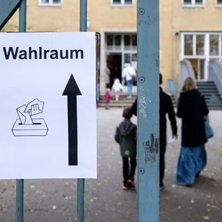 Ein Schild mit der Aufschrift "Wahlraum" hängt an einem Tor vor einem Wahllokal im Stadtteil München-Neuhausen. 