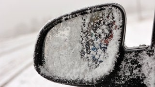 Schnee liegt auf dem Außenspiegel eines Autos (Symbolbild).