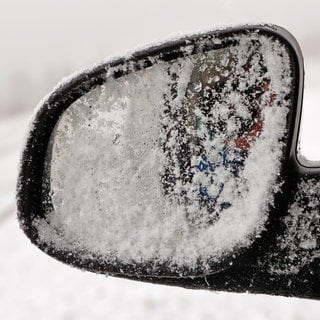 Schnee liegt auf dem Außenspiegel eines Autos (Symbolbild).