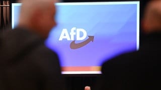 Beim Landesparteitag der AfD Baden-Württemberg in der Rheinhalle in Ketsch (Rhein-Neckar-Kreis) gehen Besucher am Logo der Partei vorbei.