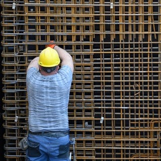 Ein Bauarbeiter beschäftigt sich auf einer Baustelle mit einer Stahlbetonwand. 