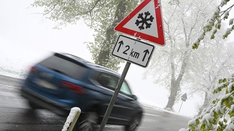 Ein Auto fährt an einem Schild vorbei, das vor Schnee auf der Schwäbischen Alb warnt. (Symbolbild)