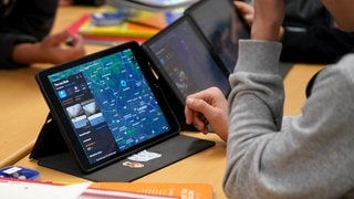 Symbolbild: Schüler arbeiten auf einer Schulbank an einem Tablet. BW will trotz des Aus der Ampel eine schnelle Umsetzung des Digitalpaket 2.0. für Schulen.