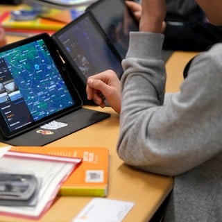 Symbolbild: Schüler arbeiten auf einer Schulbank an einem Tablet. BW will trotz des Aus der Ampel eine schnelle Umsetzung des Digitalpaket 2.0. für Schulen.