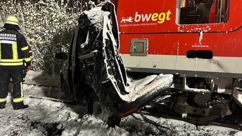 Ein Auto und ein Zug stehen nach einer Kollision auf den Gleisen.