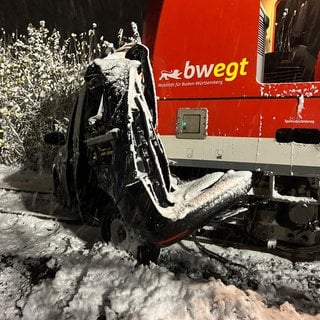 Ein Auto und ein Zug stehen nach einer Kollision auf den Gleisen.