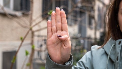 Eine emporgestreckte Hand mit sich langsam schließender Faust: Ein heimliches Handzeichen, mit dem Opfer häuslicher Gewalt auf sich aufmerksam machen können.